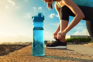 Woman tying her shoe in front of water bottle