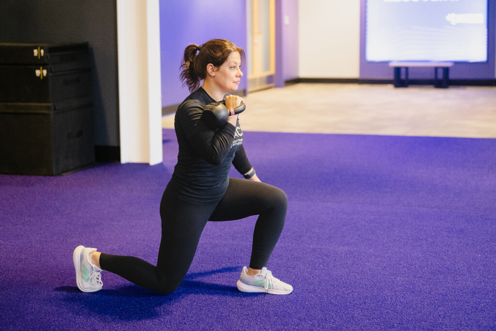 A fitness coach in a gym, ready to demonstrate functional training exercises, wearing workout gear with "I'm Your Coach" branding.