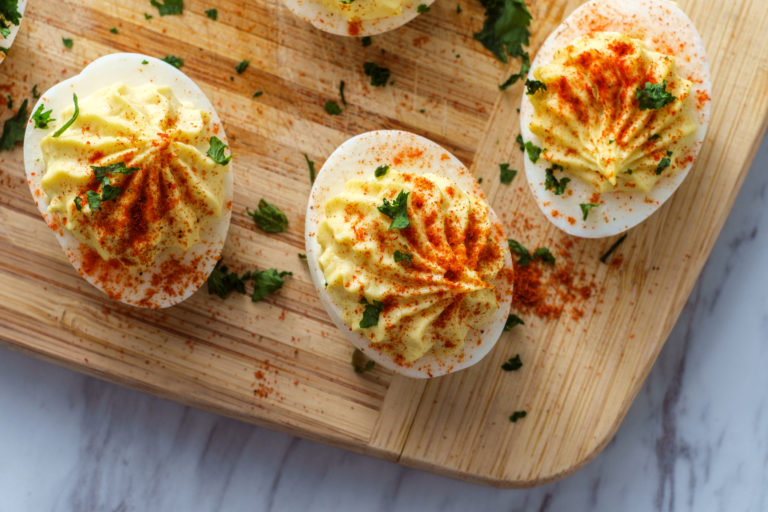 Deviled eggs with paprika on a cutting board.