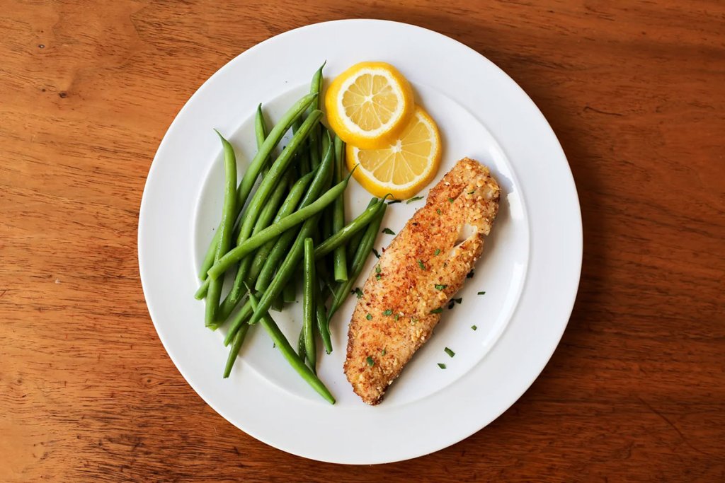 Plate of almond-crusted tilapia with a side of green beans.