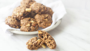 Apple butter oatmeal cookies on a white plate, one has been broken in half.