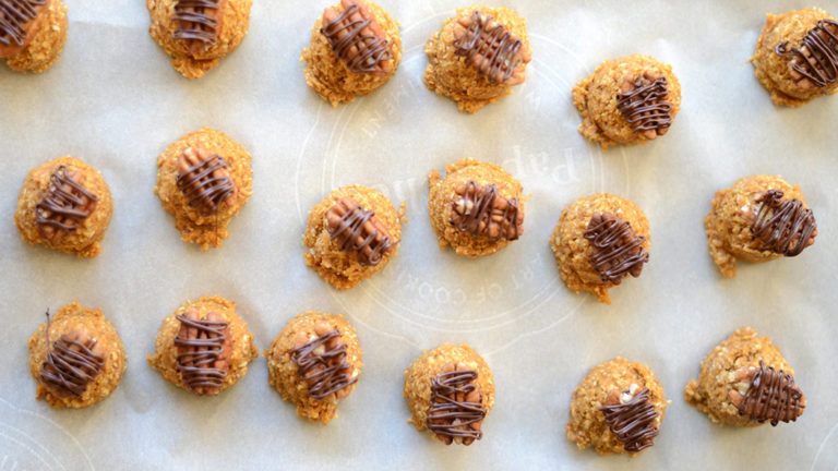 Tray of frozen pumpkin bites with pecans and chocolate drizzle.