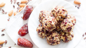 White plate full of cherry bites with dates and nuts to the side.