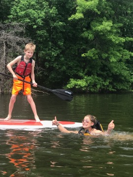 coach-heather-in-a-lake-while-paddle-boarding - Anytime Fitness