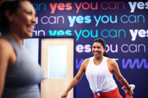 Two women stretching and laughing at the gym.