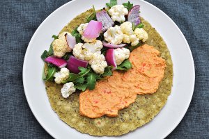 Open-face wrap, with red bell pepper hummus, roasted cauliflower and onions, and fresh arugula.