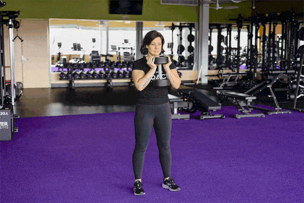Coach Heather demonstrating a Goblet Squat with Dumbbell in a gym setting.