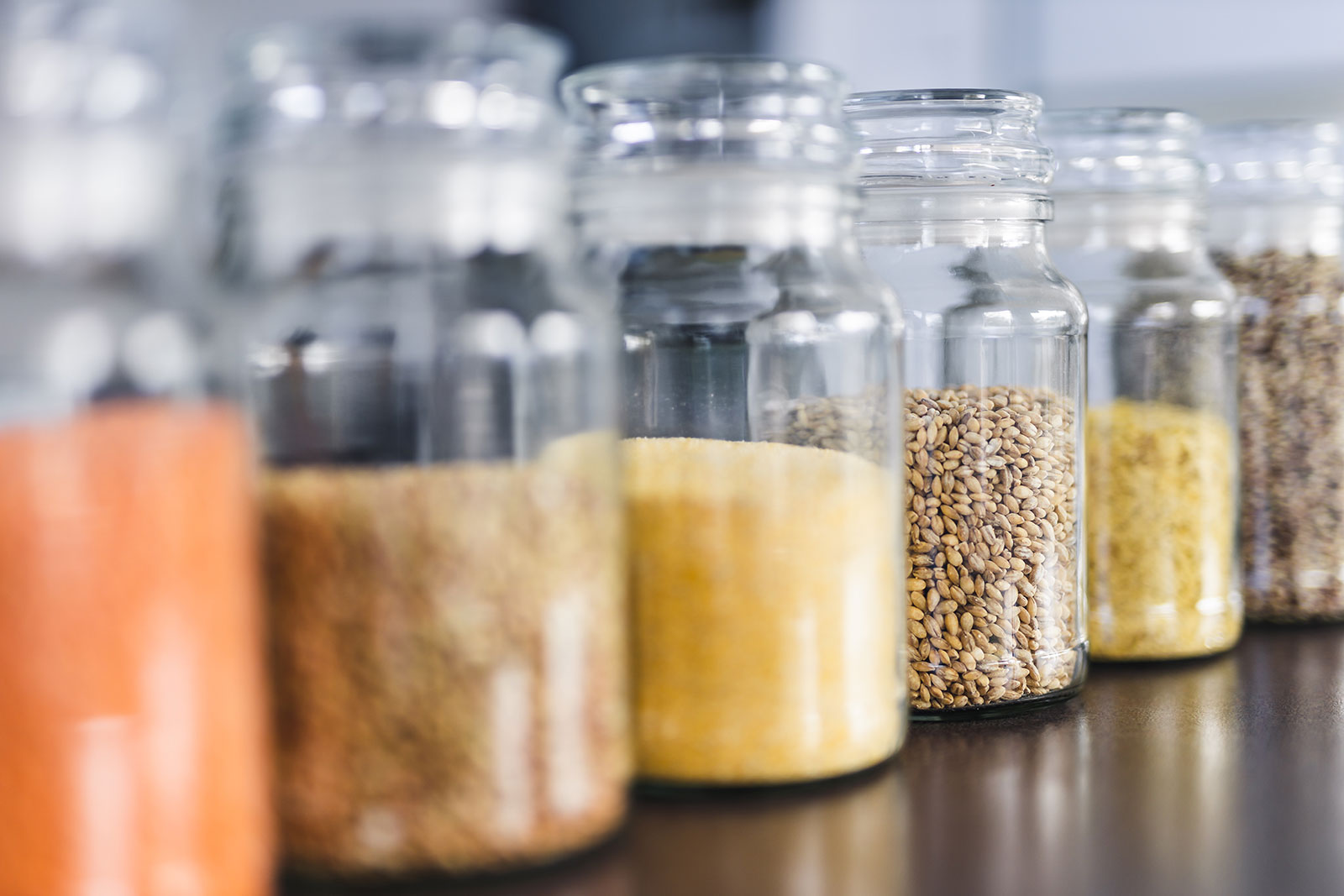Glass jars of whole grains sitting on a counter.