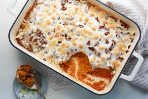 Sweet potato casserole in a baking dish, a scoop removed, with a serving spoon sitting next to the dish.