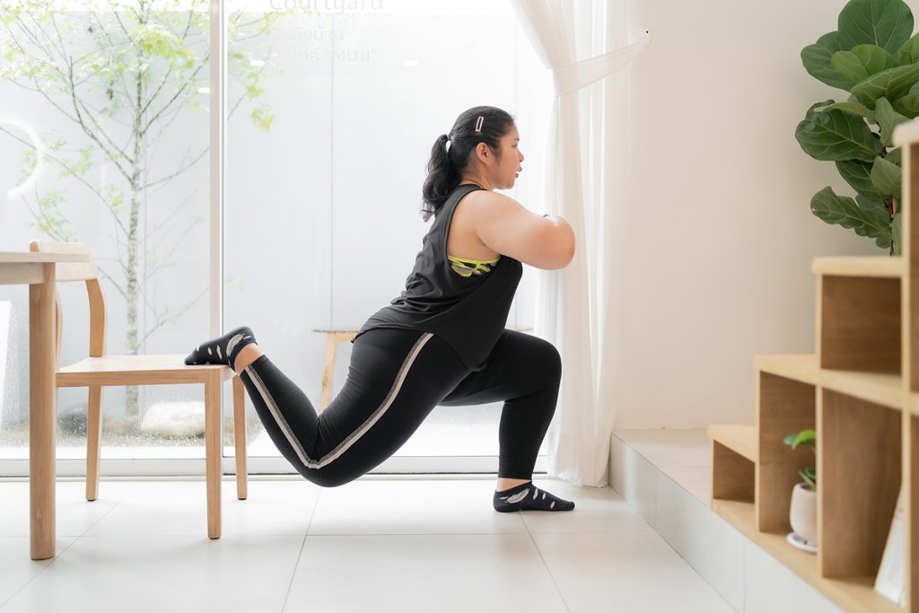 Woman doing a workout at home, using a chair.