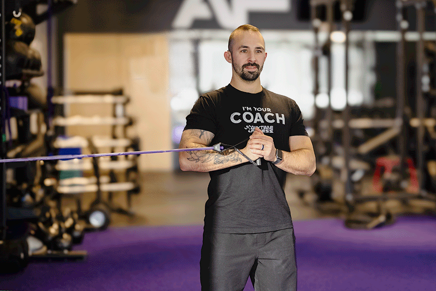 Anytime Fitness Coach Mike demonstrating a band anti rotation hold in a gym setting.