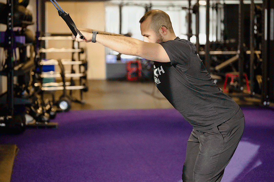 Anytime Fitness Coach Mike demonstrating a straight arm pulldown in a gym setting.