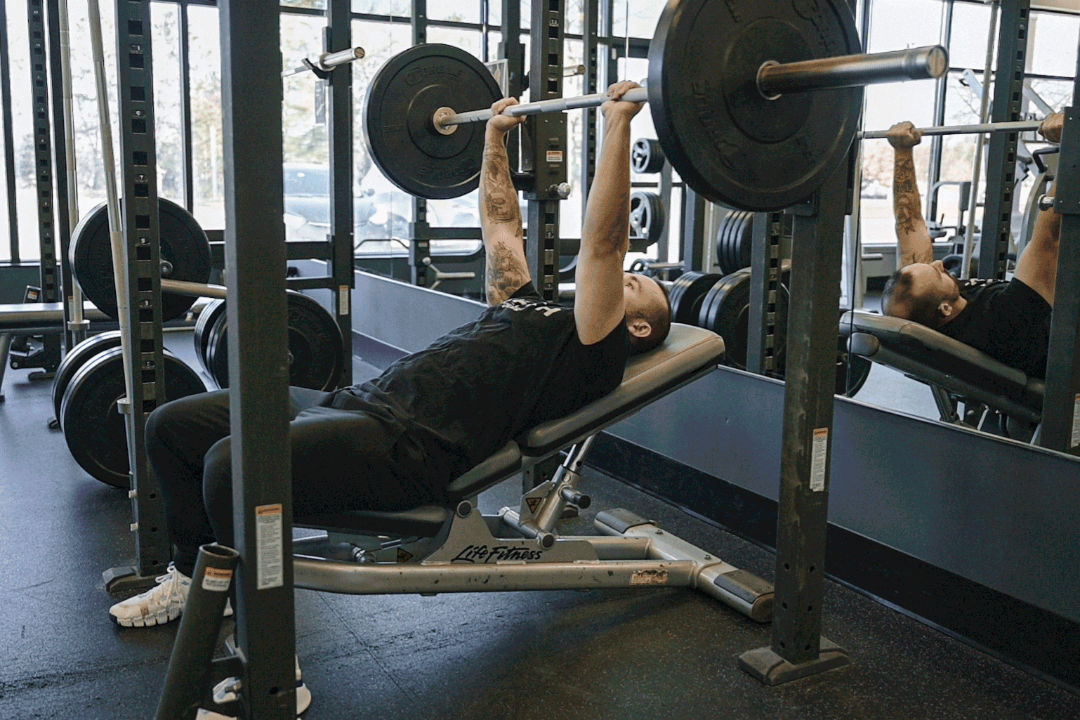 Coach Mike demonstrating an incline barbell bench press in a gym setting.
