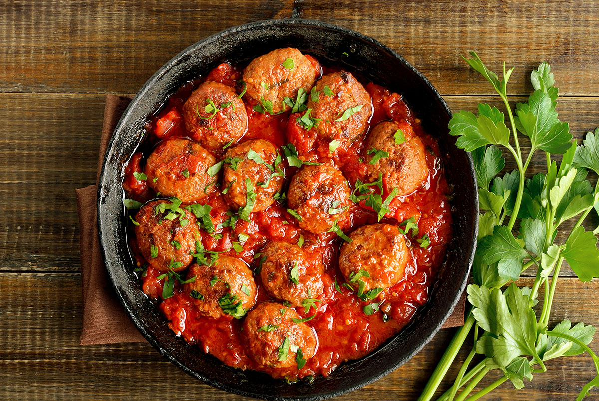 Meatballs with tomato sauce in frying pan.