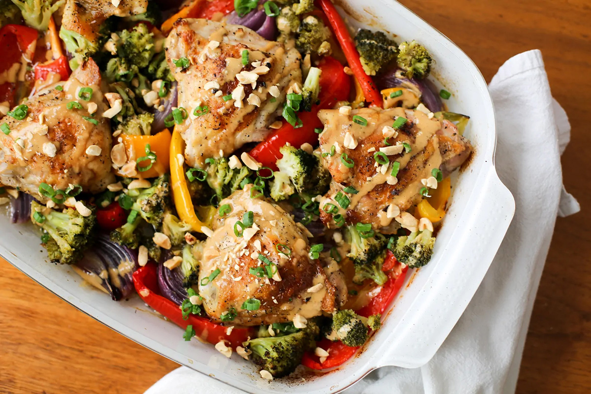Dish filled with crispy peanut chicken thighs and vegetables.