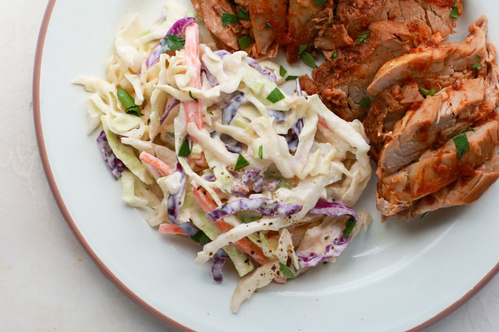 Coleslaw side-dish plated with meat.