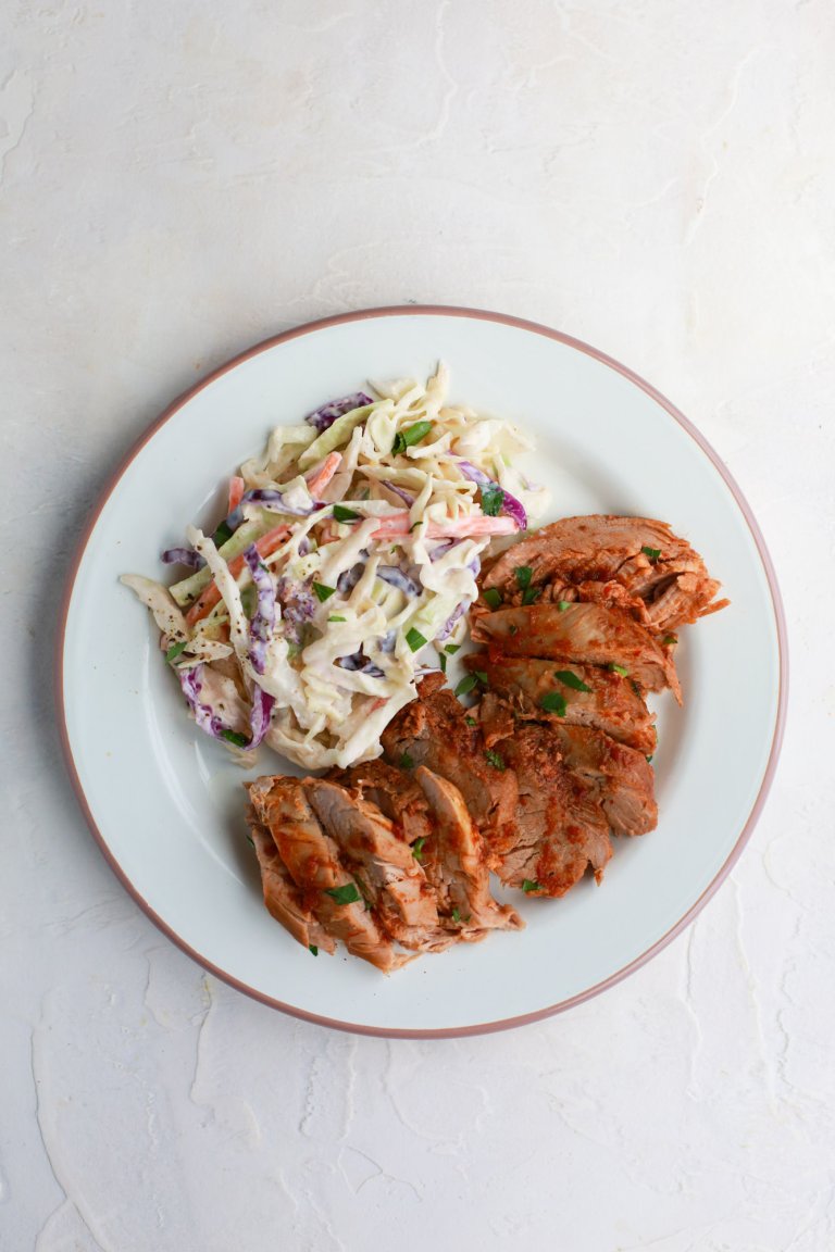 Side of coleslaw paired with meat on a plate.