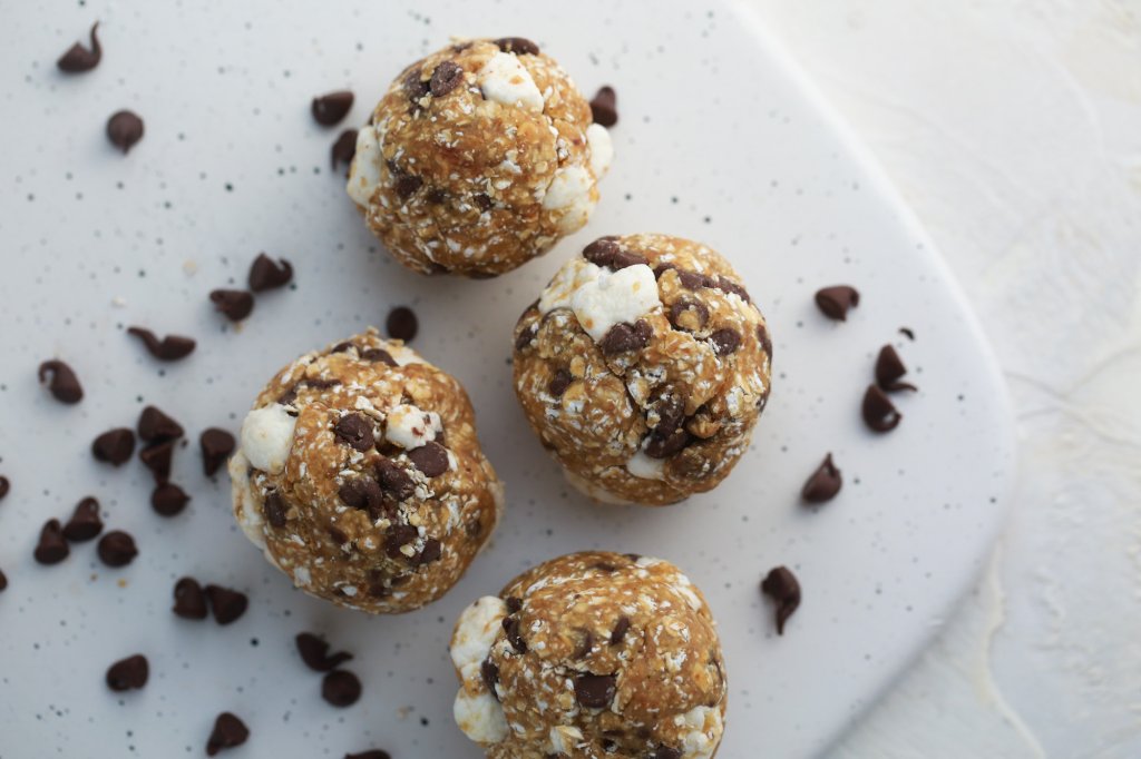 S'mores protein bites made with mini-marshmallows, chocolate chips, quick oats and graham cracker crumbs, arranged on a plate.