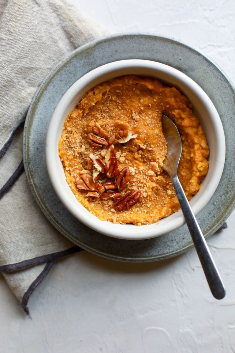 Bowl of pumpkin pie-flavored oats with chopped pecan topping.