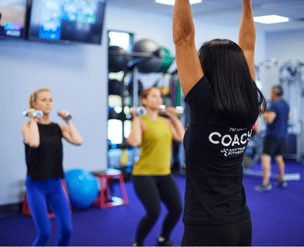 Coach and students working out with dumbbells in the background