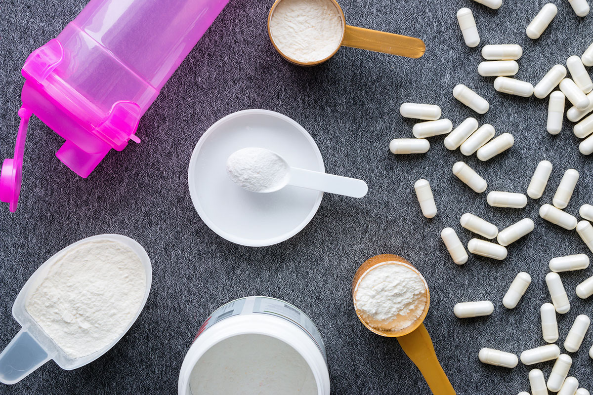 A flat lay of pre-workout powders, measuring scoops, capsules, and a shaker bottle, illustrating various forms of pre-workout supplements.