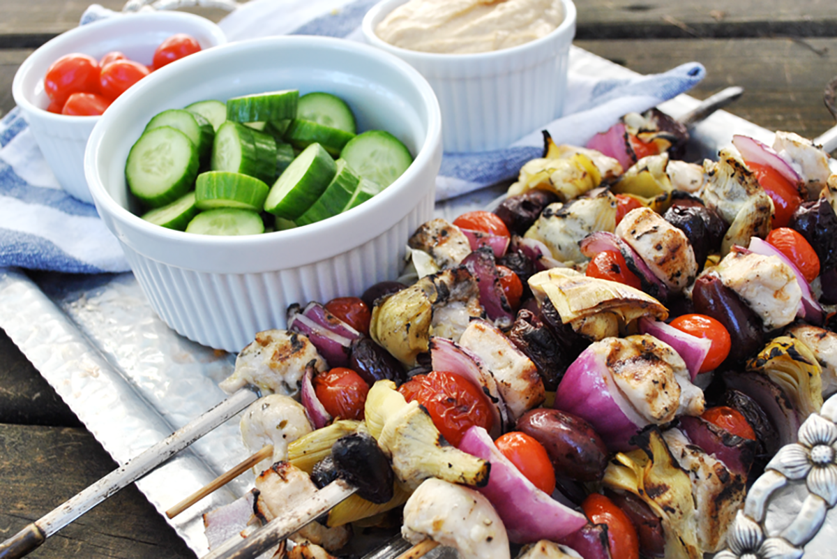 Grilled Greek chicken and vegetable kabobs served with cucumber slices and cherry tomatoes, ideal for a healthy holiday meal.