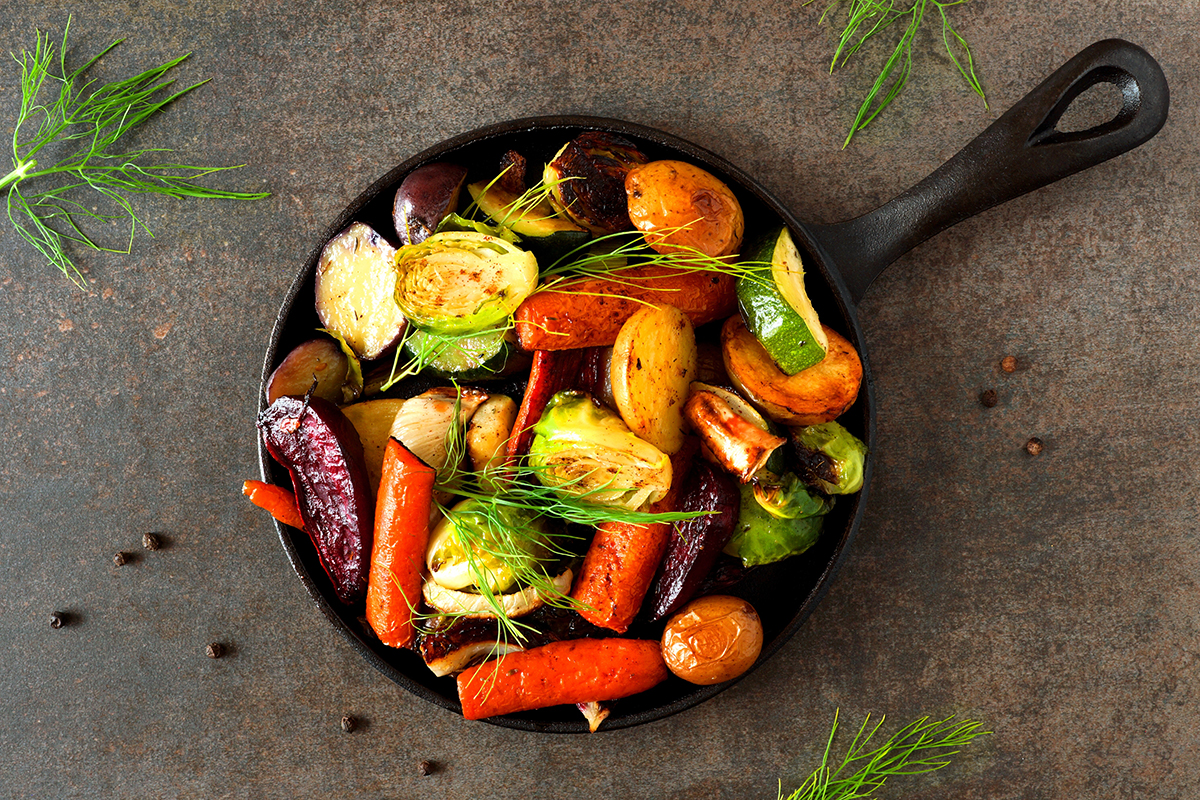 Colorful roasted vegetables in a cast iron skillet, including carrots, Brussels sprouts, and zucchini, perfect for a nutritious side dish.