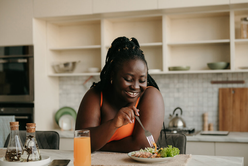 Smiling woman enjoying a healthy meal at home, highlighting balanced nutrition while taking GLP-1 medications for weight management.