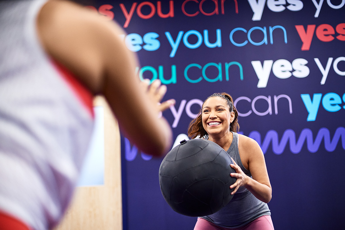 Women engaging in a fun medicine ball workout at the gym, promoting fitness, strength training, and motivation in a supportive environment.